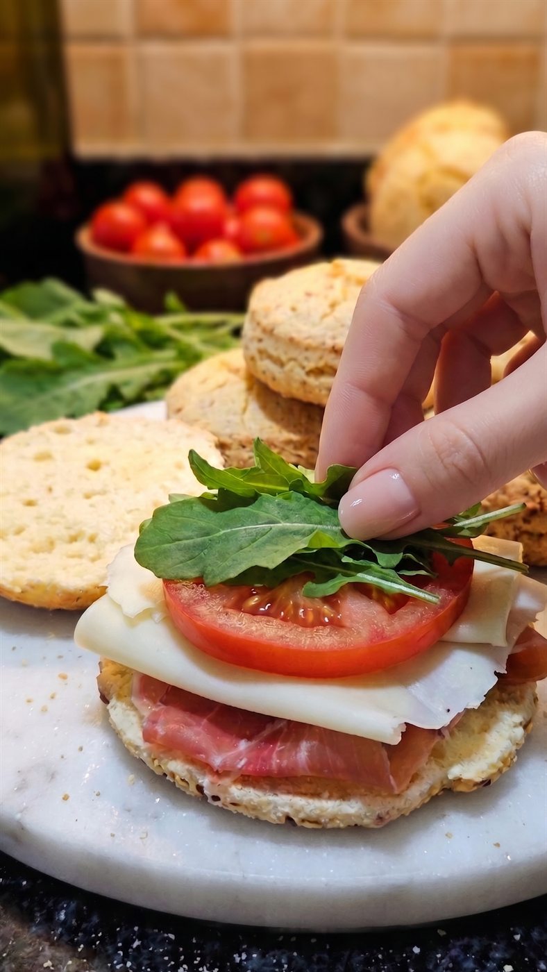 ChipaPan de Chipa Mix armado como sándwich con jamón crudo, queso, tomate y rúcula
